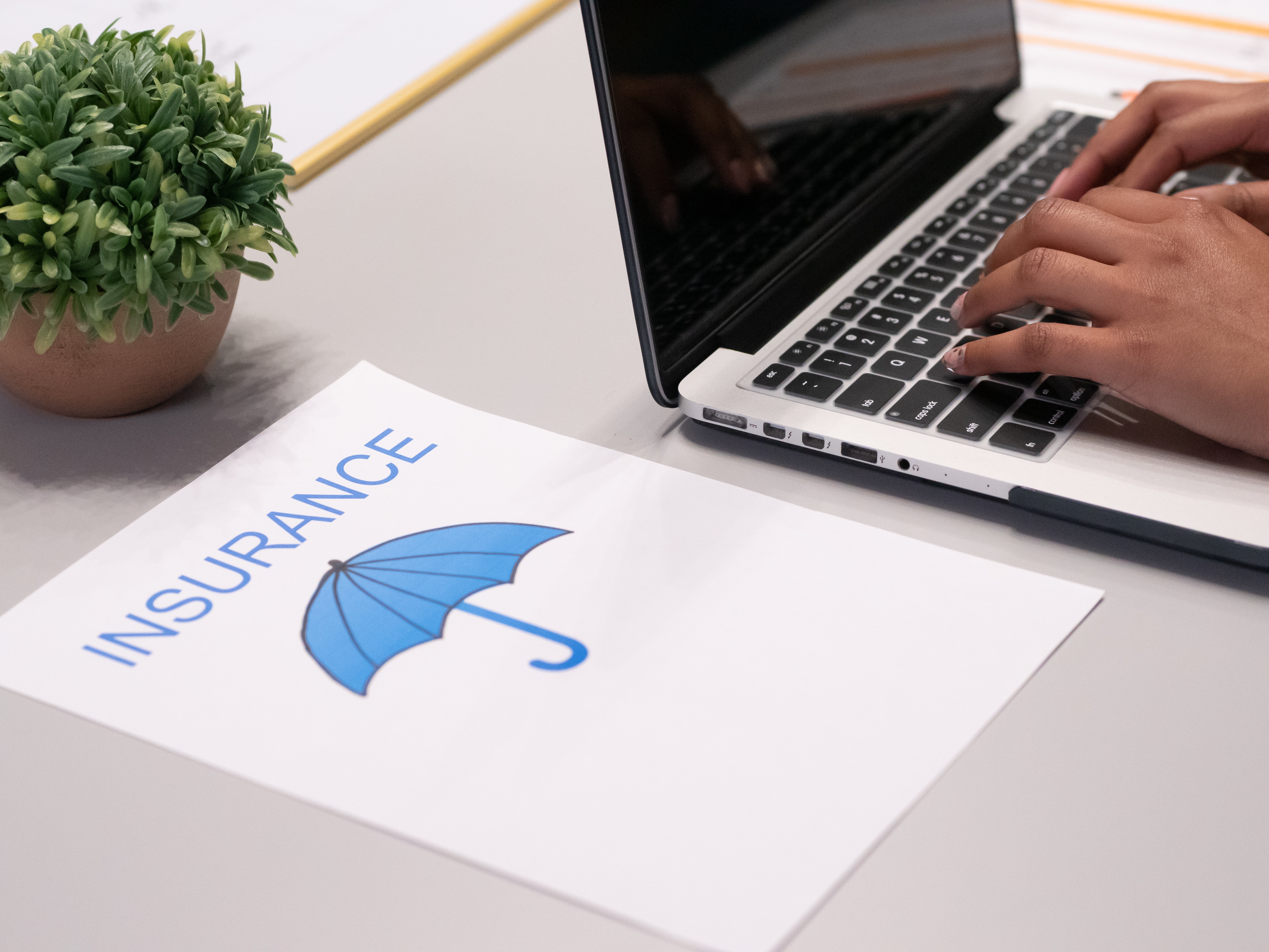Insurance paper next to person typing on a laptop.